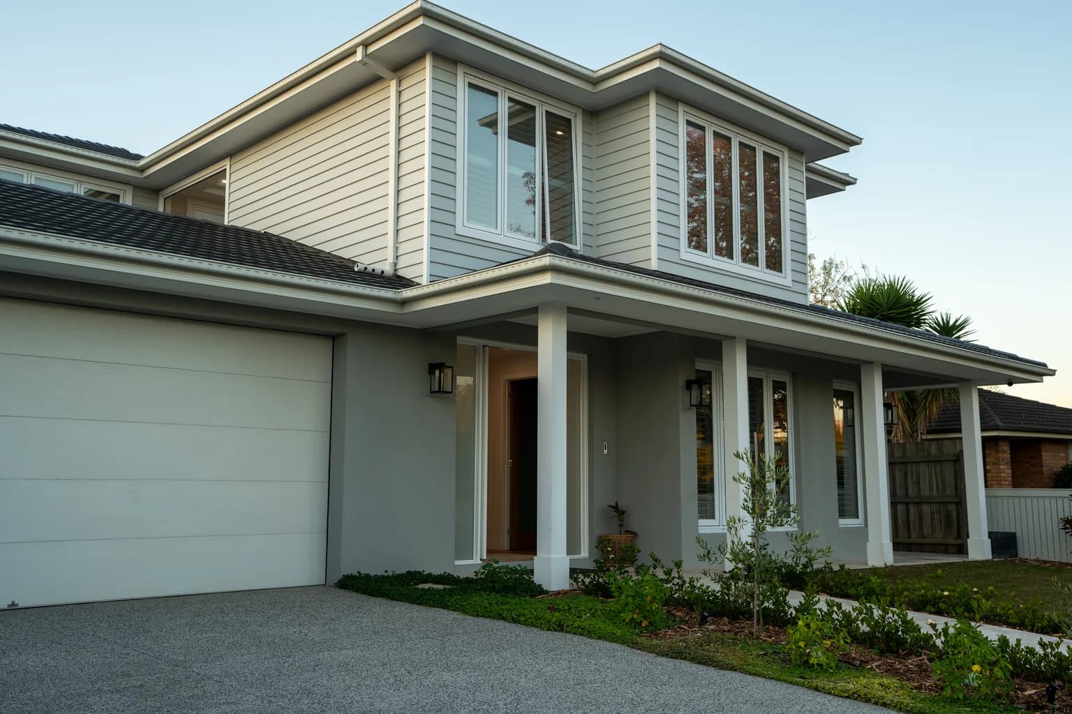 The Willow, a two storey Hamptons-style knockdown rebuild by NE Homes in Rowville, with a white portico and weatherboard upper floor