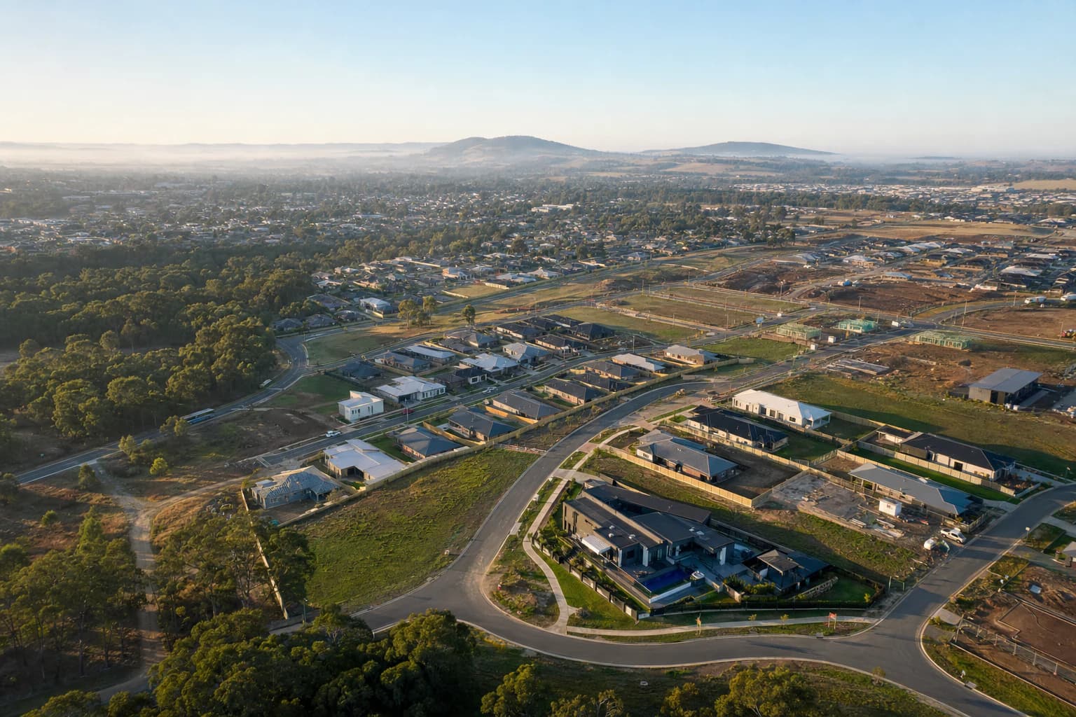 An aerial view of a new residential estate, with recently completed single-storey homes along curved streets and vacant lots still being released at the edge