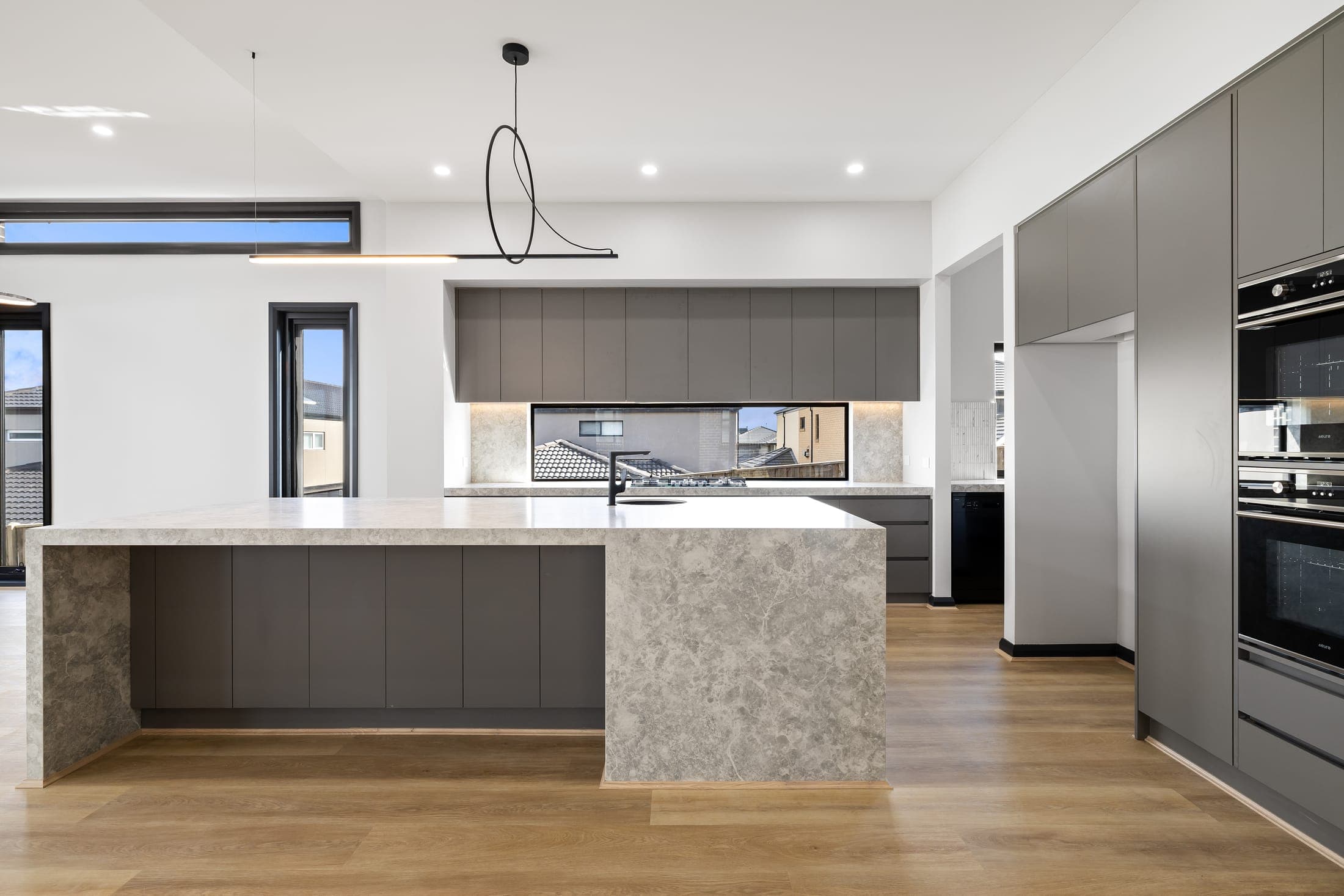 Dark kitchen with waterfall stone island in a sloping block home, Old Berwick