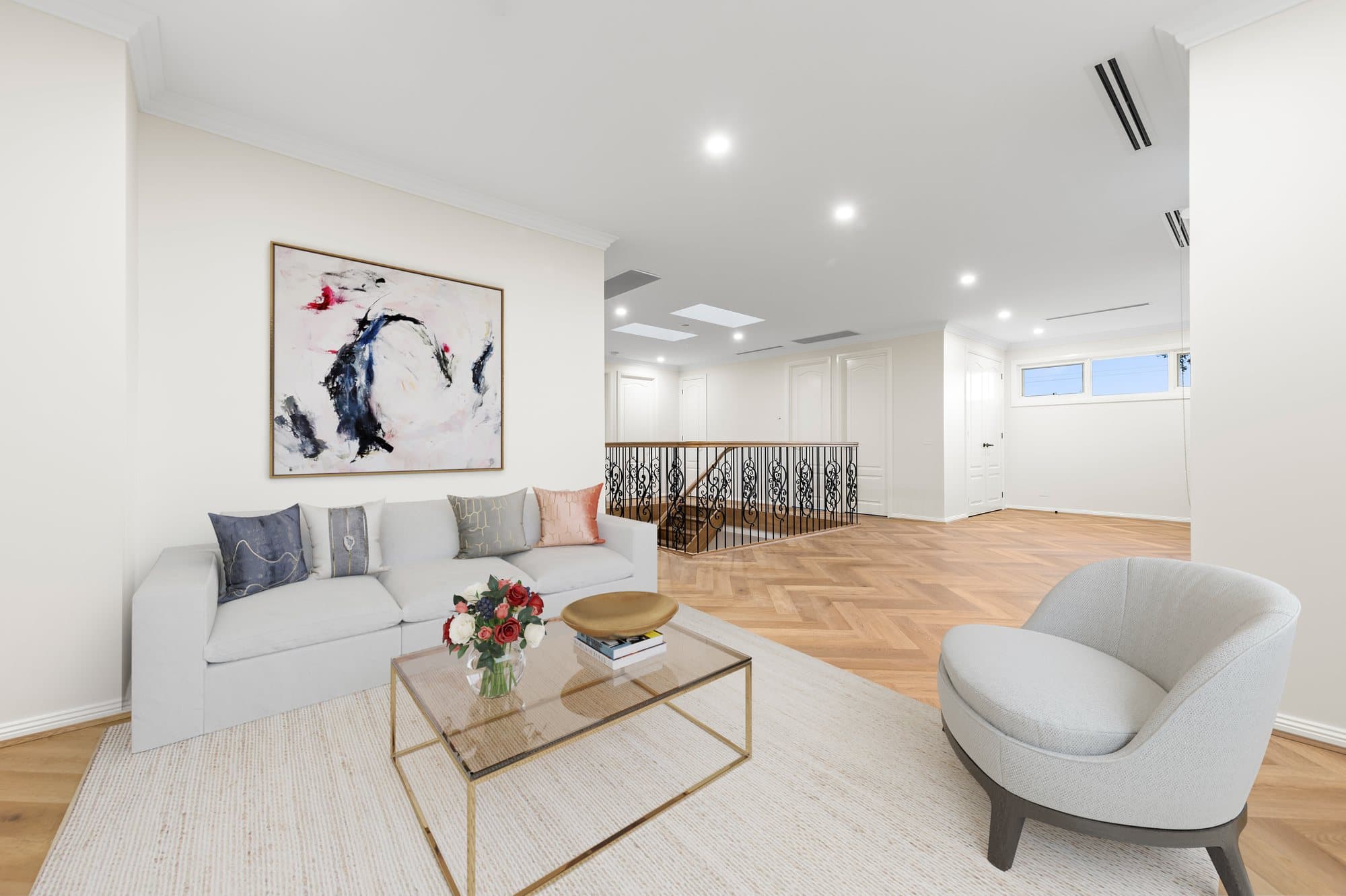 Upstairs living area with herringbone timber floor and a curved stair balustrade in The Marquise, Oakleigh South